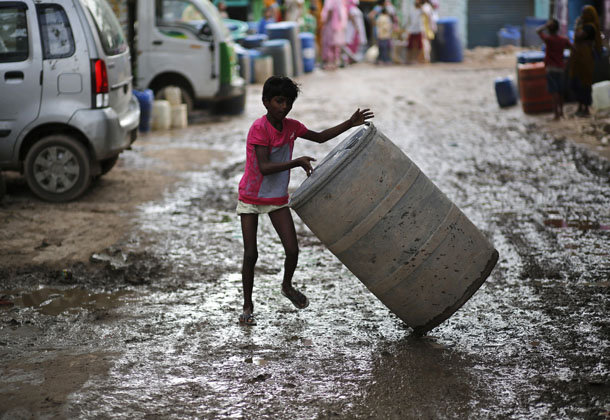 Мальчик катит бочку, чтобы наполнить ее чистой питьевой водой. Нью-Дели